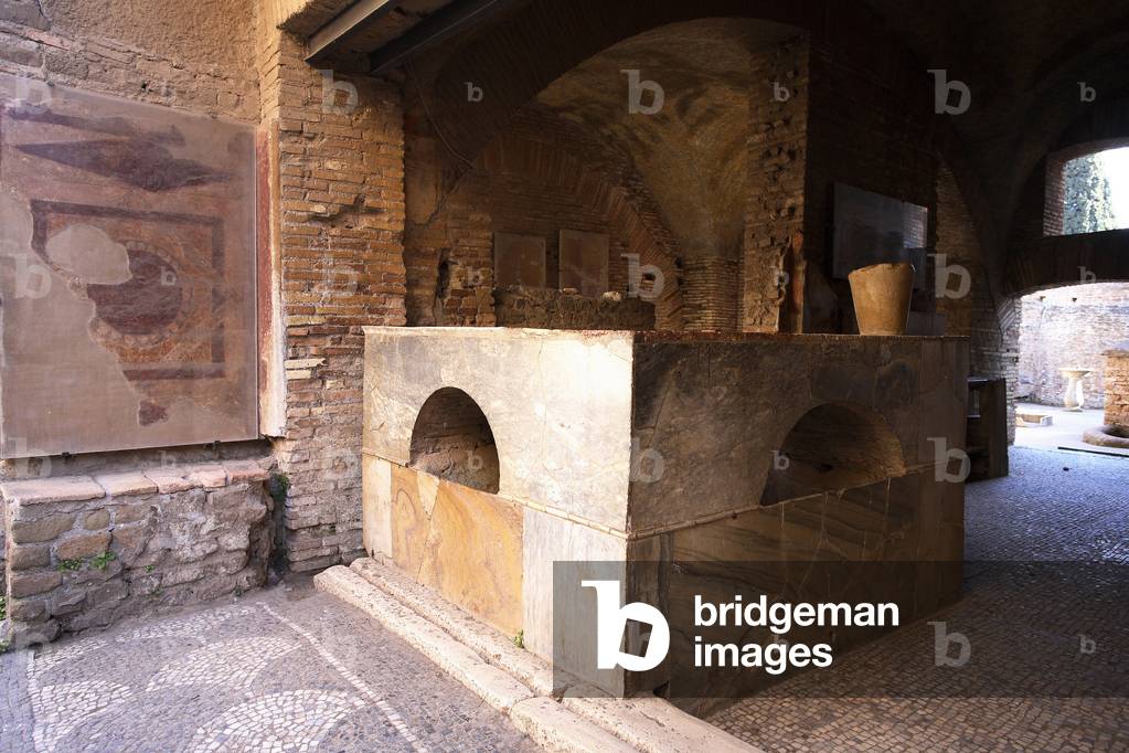 Thermopolium: Echoppe on the ground floor of a building that sells hot drinks and takeaways. The counter at the entrance and the courtyard from the insula to the background/Ancient Ostia/Italy