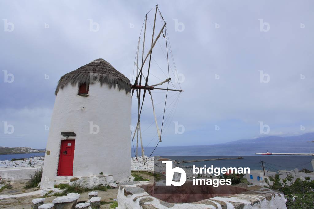 Old traditional Windmill and Cityscape. The main village of Mykonos town (Chora) . Cyclades, Mykonos, Greek islands, Aegean sea.