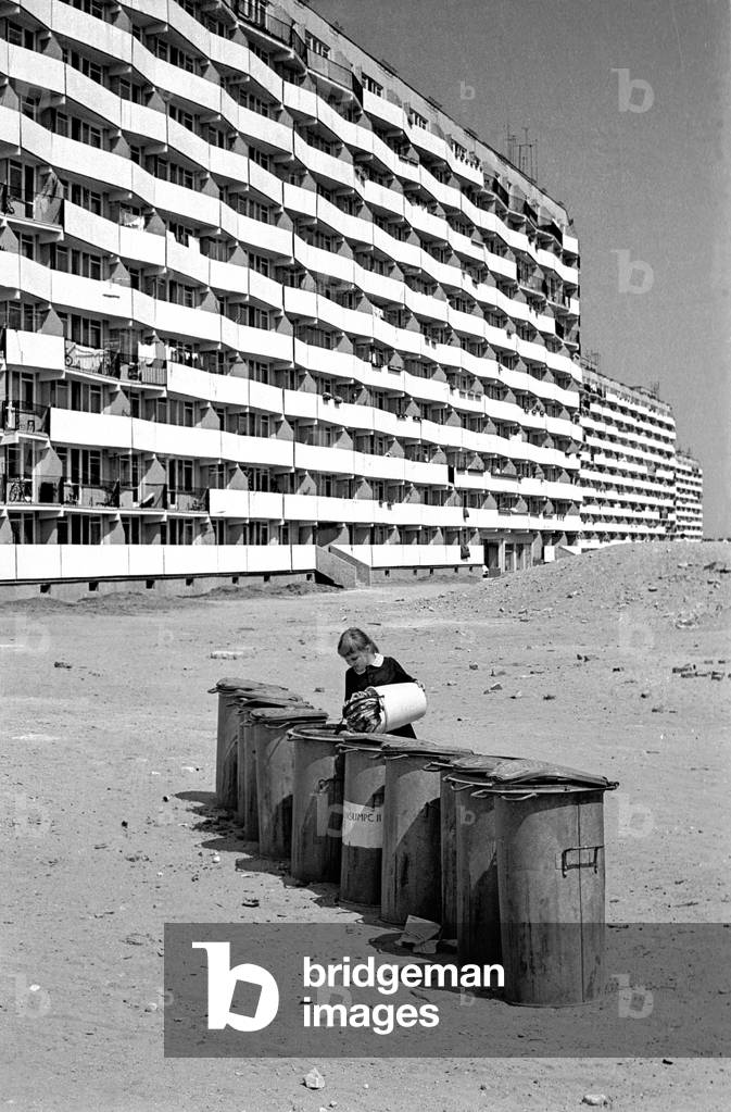 Gdansk, Poland, 04.1972. Housing Estate of very characteristic buildings (Falowce) which design was inspired by the shape of sea waves. In photo - A girl placing rubbish in a litter bin in-front of the building. 