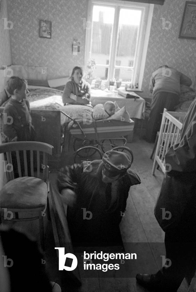 Poland, second part of 1970s. Citizens Militia (Milicja Obywatelska) operation against people producing bootleg vodka at home. Militia officer going down to an underground chamber in search of alcohol. 