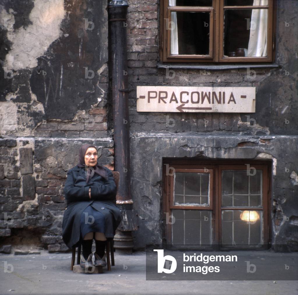 Warsaw, Poland, 1972. Praga district. Old woman sitting on a stool and resting in her yard. 