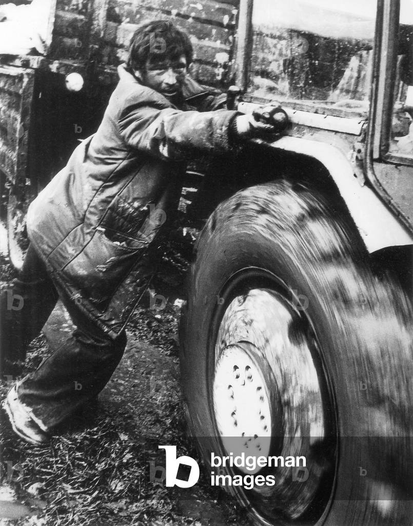 Poland, 1970s. A farmer helps to pull out a tractor from the mud. 