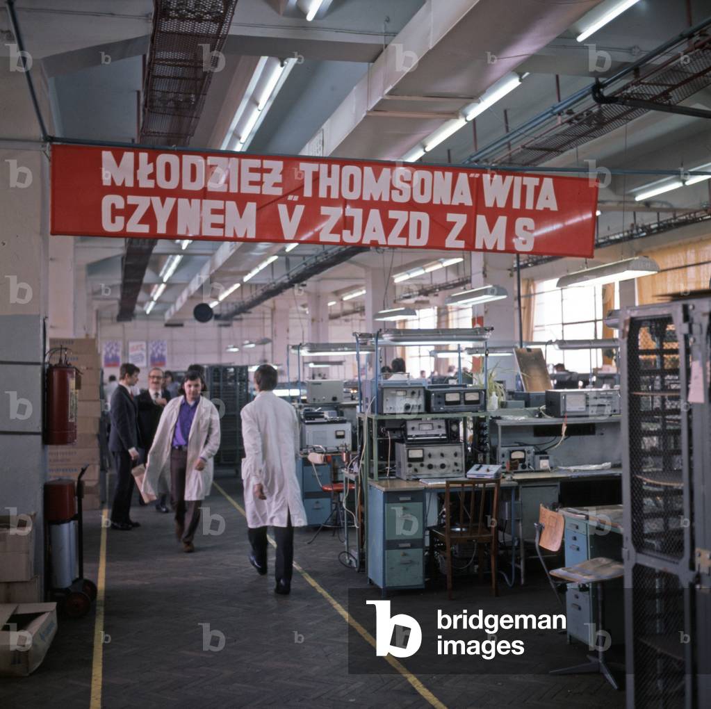 Warsaw, Poland, 10.1971; Workshop hall in Marcin Kasprzak Radio Plant. Propaganda slogan on banner reads - â€œYouth of Thomson factory welcomes with action the 5th convention of Socialistic Youth Unionâ€ù (ZMS - Zwiazek Mlodziezy Socjalistycznej). 