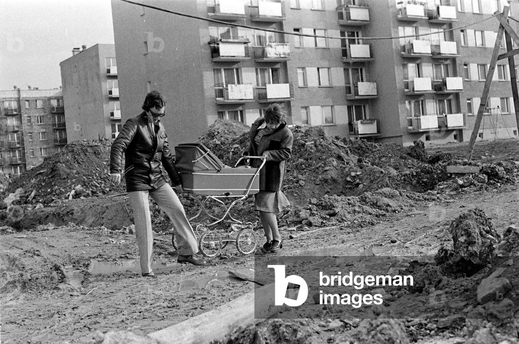 Warsaw, Poland, 1978. Married couple walking with a pram in the mud in Stegny. 