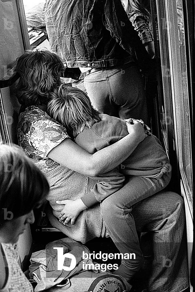 Poland, summer 1977. Mother with child sitting on a crowded corridor in a long distance passenger train. 