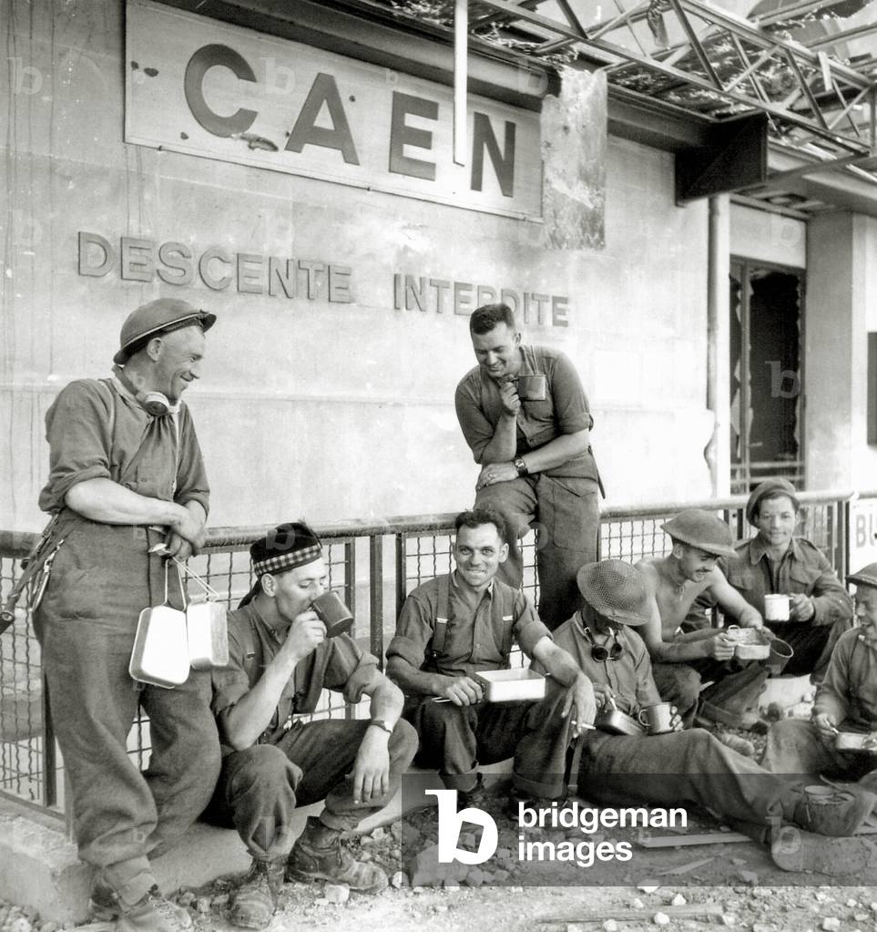 Highlanders of the Canadian Infantry take a meal at Caen, 1944 (b/w photo)