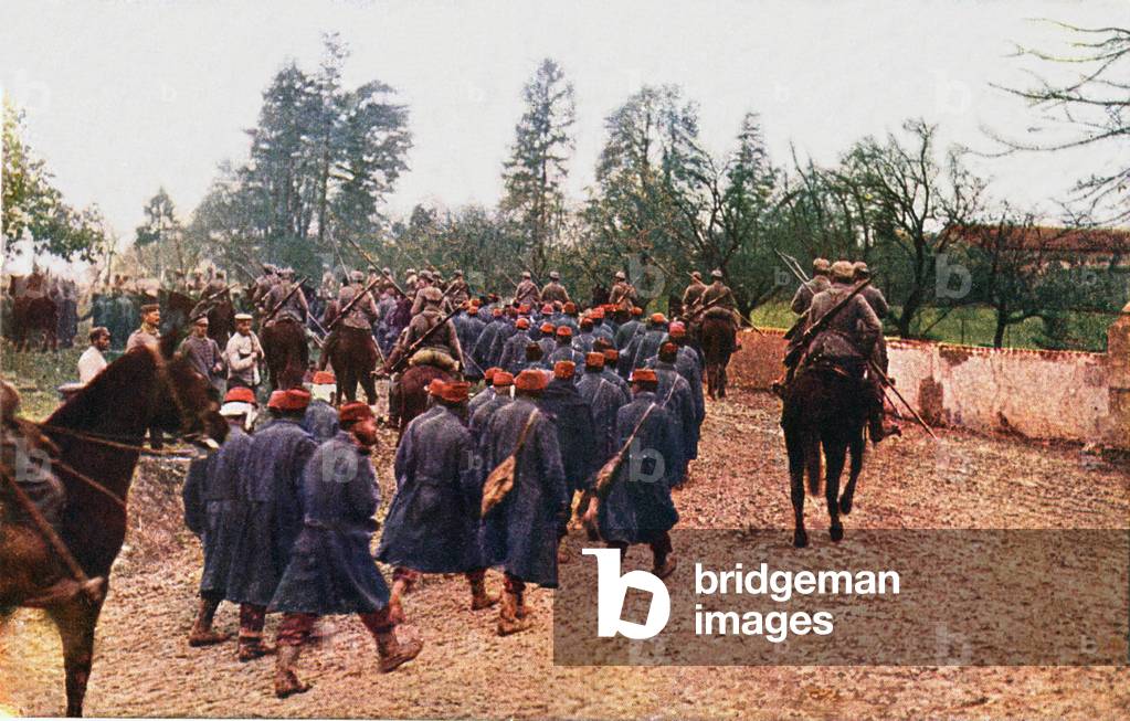 French prisoners of war are marched through a village by German lancers on horseback, 1915 (colour litho)