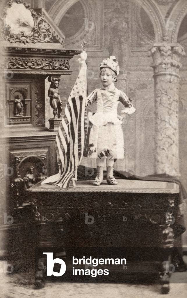 DWARF, c.1880 Portrait of a dwarf woman standing on a desk next to an American flag. Carte de visite from a photography studio in New York City, c.1880.