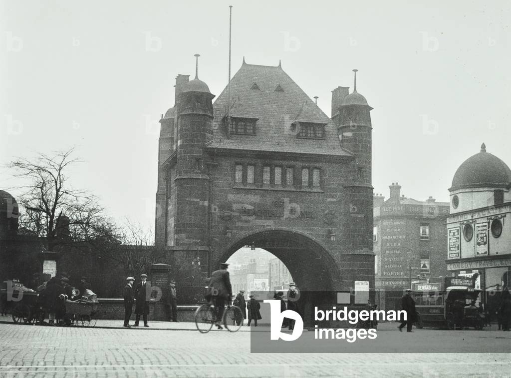 Blackwell Tunnel: entrance arch, people and traffic, a cyclist heads towwards the arch, 1920 (b/w photo)