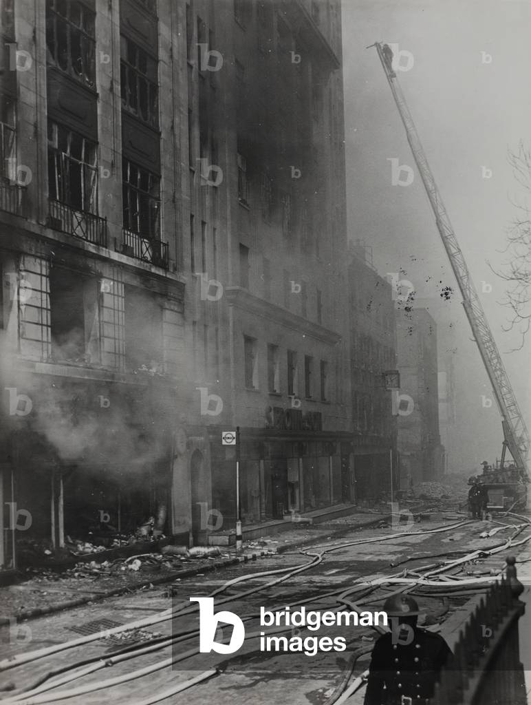 View of Houndsditch from Aldgate showing bomb damage and firemen tackling buildings still on fire, 1941 (b/w photo)
