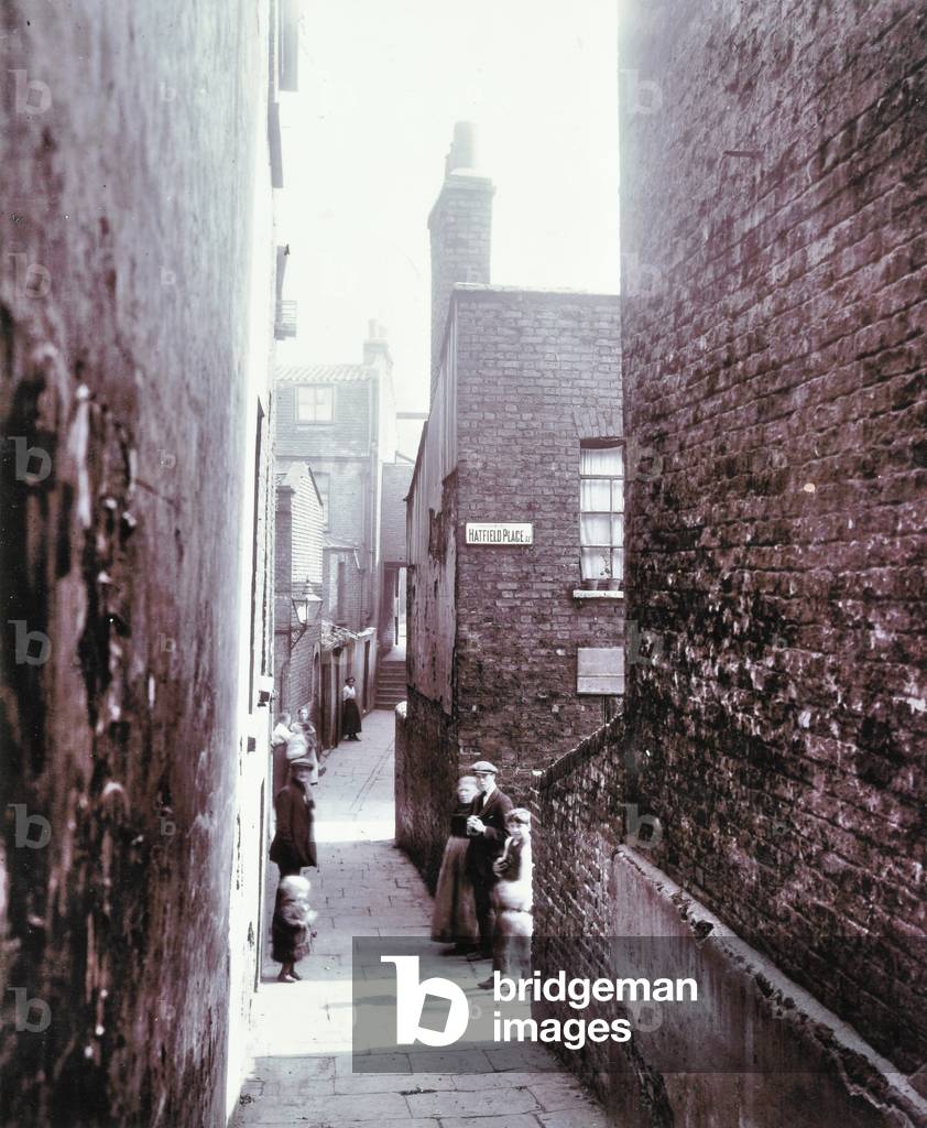 An alley off Hatfield Place with men and women posing for the camera, London, 1900 (b/w photo)