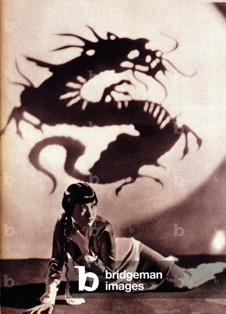 Portrait of American actress Anna May Wong (1907-1961), behind her the shadow of a Chinese dragon, in the 1920s