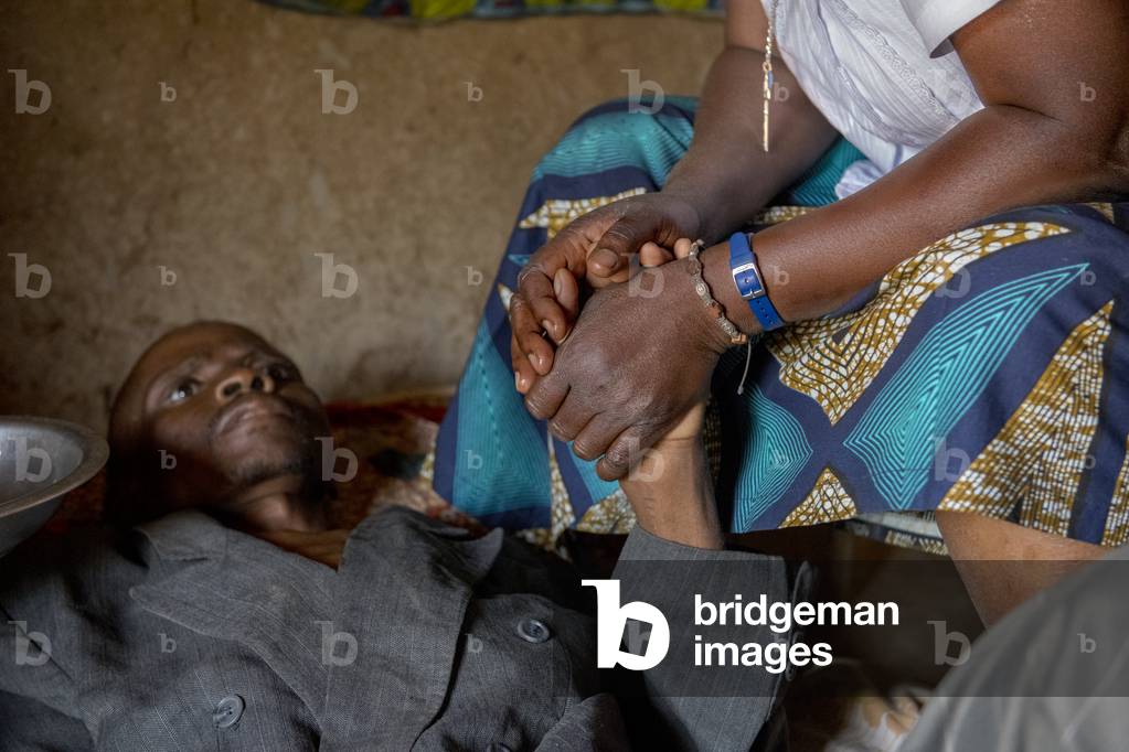 Sister Marie Stella comforting Jean, a 42-year-old man dying of AIDS in his home place. Vivre dans l'Esperance (living with hope) NGO. Village near Dapaong, Togo.