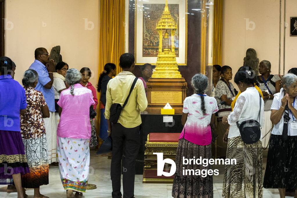 Buddhist visitors praying in front of a reliquary, India (photo)