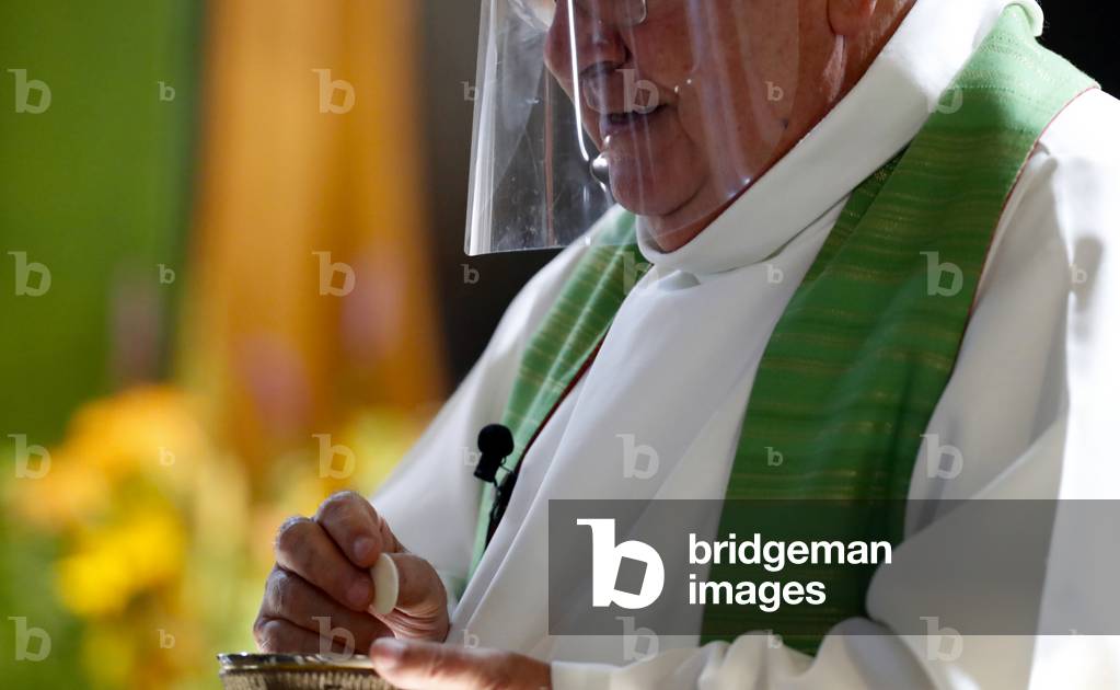 Catholic church during covid-19 epidemic. Sunday mass. Priest giving Holy Communion.  France.