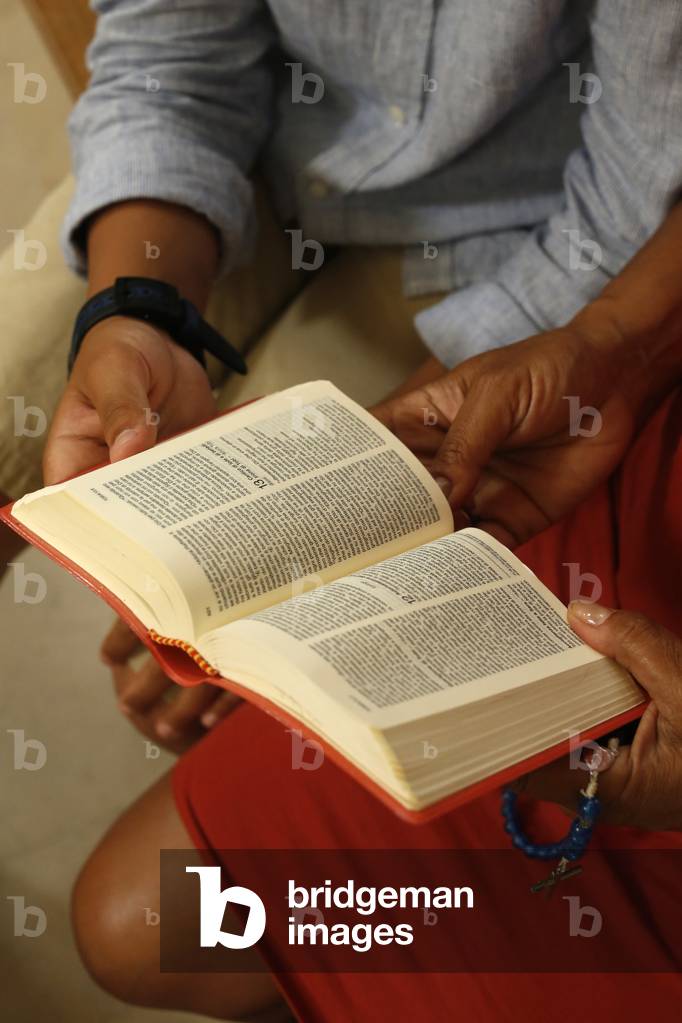 Mother and son reading the bible in a church in Lecce, Italy, 2019 (photo)