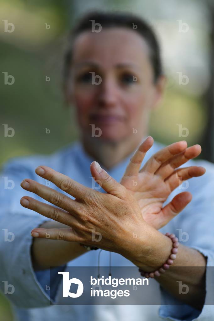 Woman practicing Qi Gong or Tai Chi exercise   in nature. Close up on hands.  France.