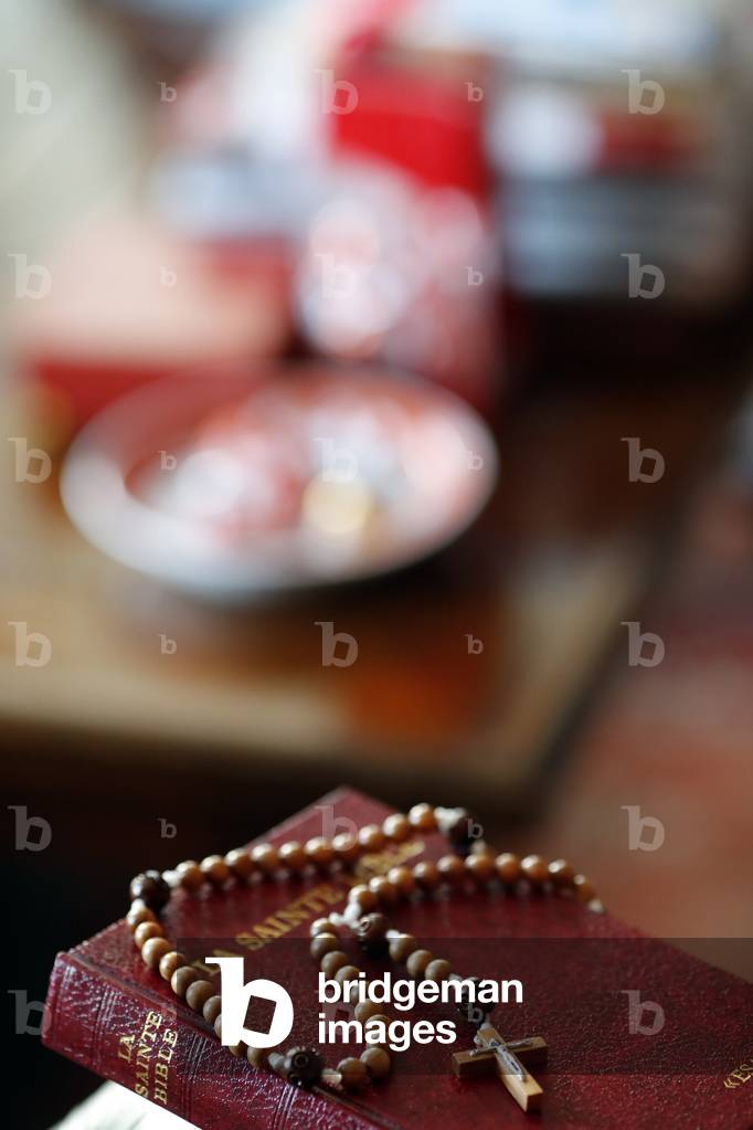 Rosary and bible on a chair in the interior of bedroom, France, 2019 (photo)