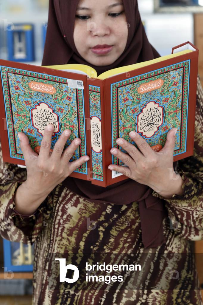 The National Mosque or Masjid Negara, Muslim woman reading the Quran, Kuala Lumpur, Malaysia (photo)