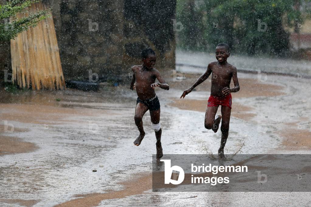 Rainy season in an african village, Boys running under the rain Togo, 2019 (photo)