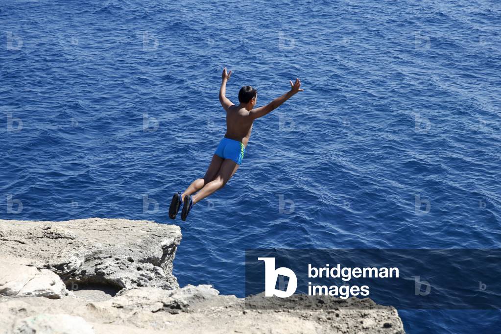 11-year-old boy jumping from a cliff into the sea in Salento, Italy (photo)