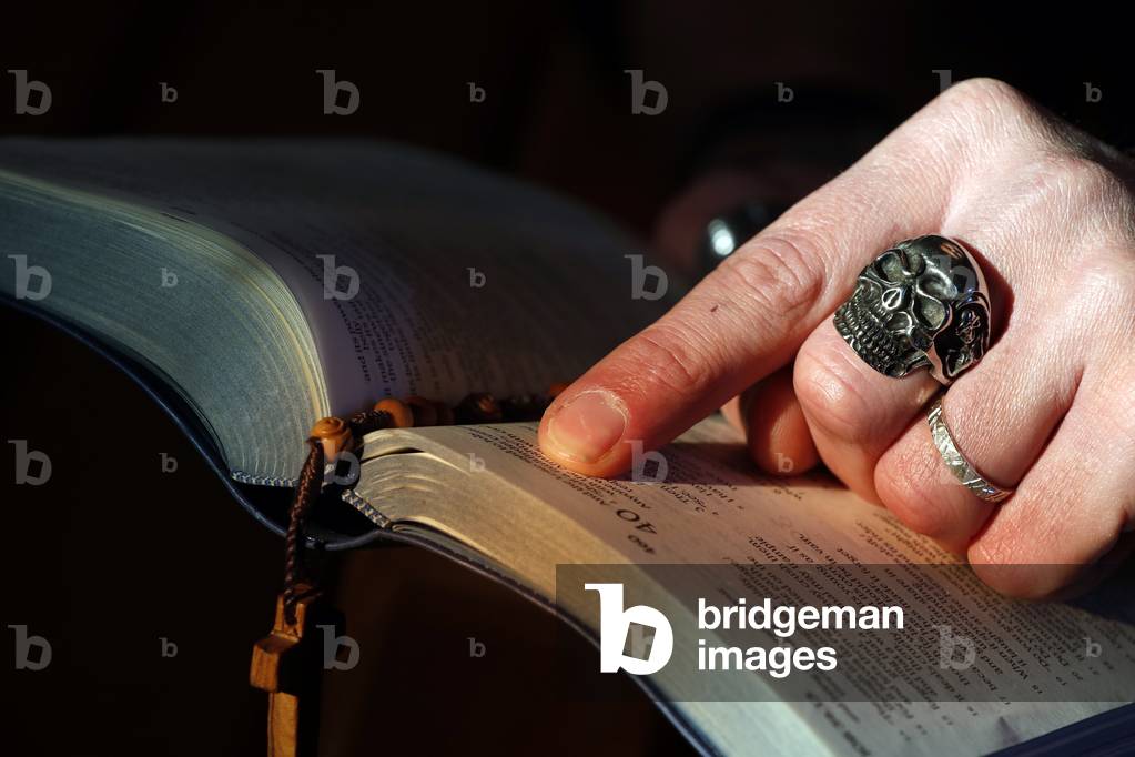 Man with skull ring reading the holy bible, France (photo)