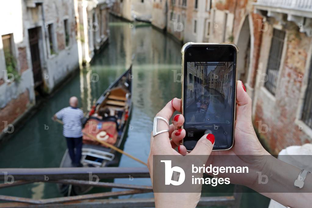 Woman making videos and photos of a gondal with a mobile phone.