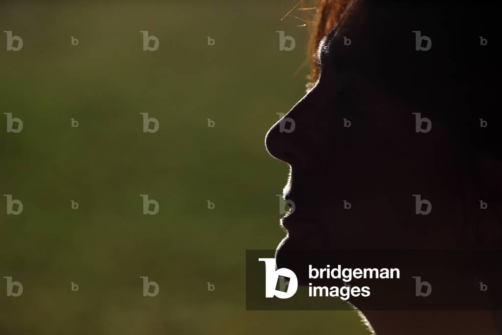 Profile view of silhouette woman standing outside  during sunset.  France.