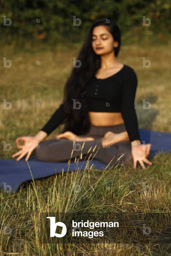 Yogini meditating in a garden in Eure, France