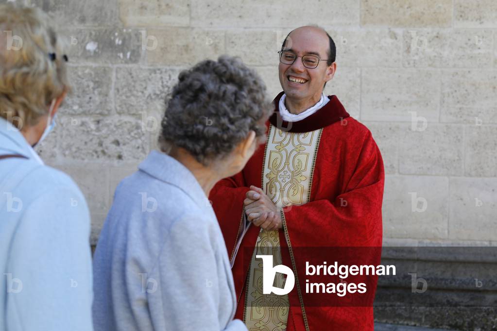 Priest greeting parishioners after Pentecost mass in St Nicolas's church, Beaumont-le-Roger, France