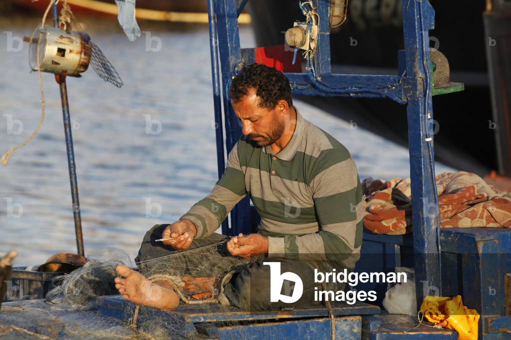Jerba fisherman mending a net on his boat, Houmt Souk, Tunisie