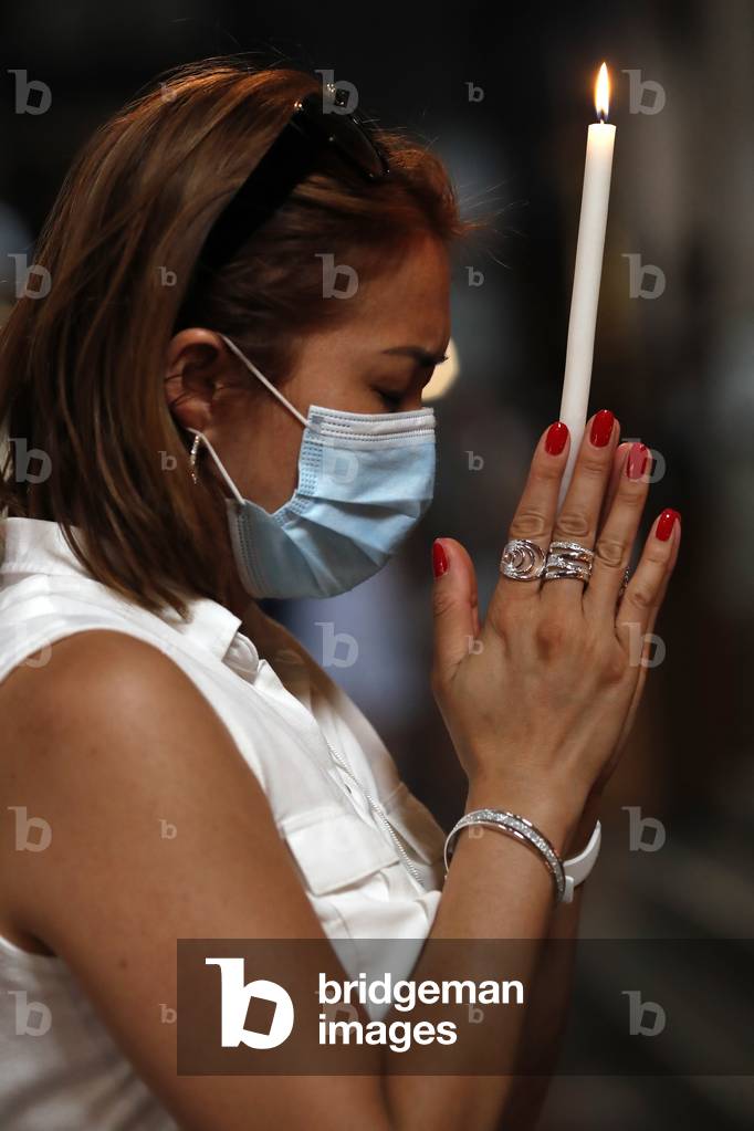 Woman with face mask praying in church during coronavirus epidemic.