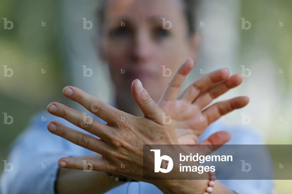 Woman practicing Qi Gong or Tai Chi exercise   in nature. Close up on hands.  France.