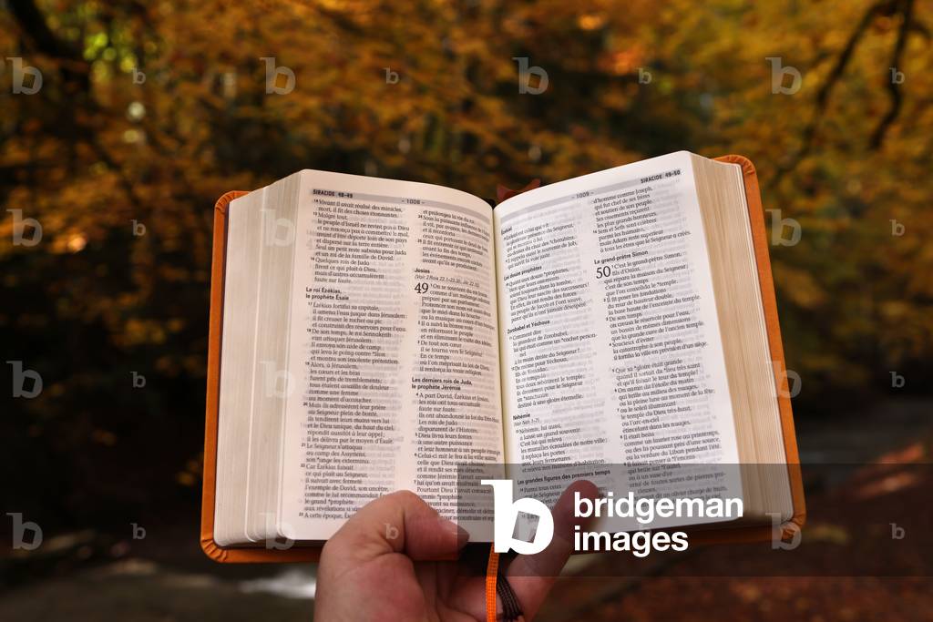 Man  holding an open bible. Forest in autumn.  France.