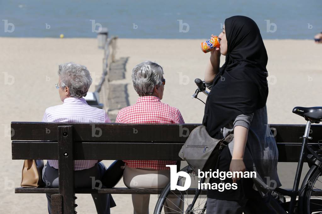 Sandy beach of the North Sea, Muslim woman drinking a soda, Knokke-Heist, Belgium