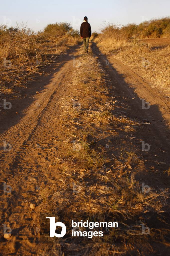 Woman walking on a dirt road, Madikwe, South Africa