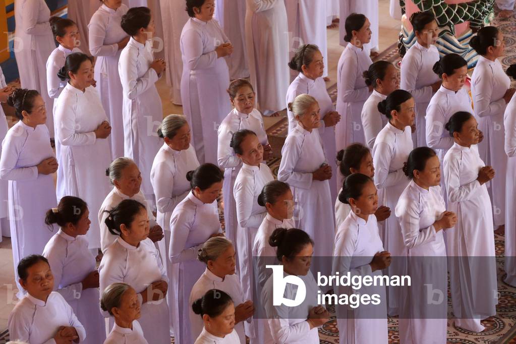 Cao Dai Holy See Temple. Praying devout women, ceremonial midday prayer. Thay Ninh. Vietnam