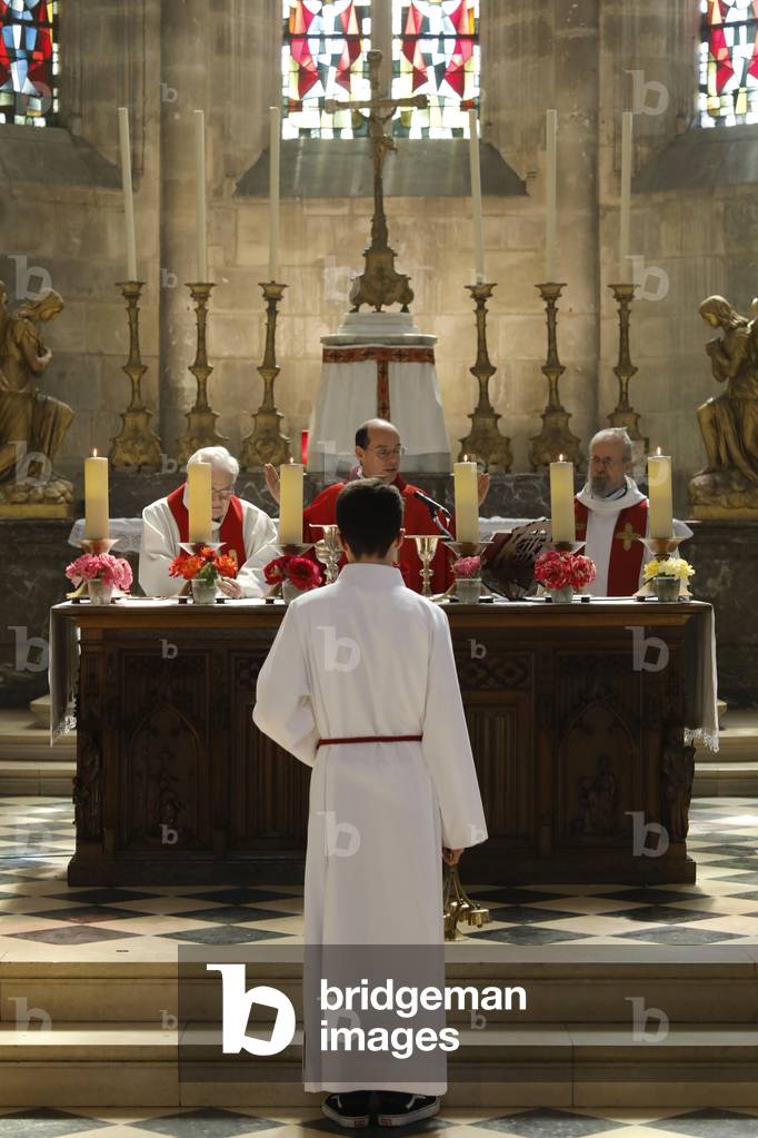 Pentecost mass in St Nicolas's church, Beaumont-le-Roger, France. Altar boy