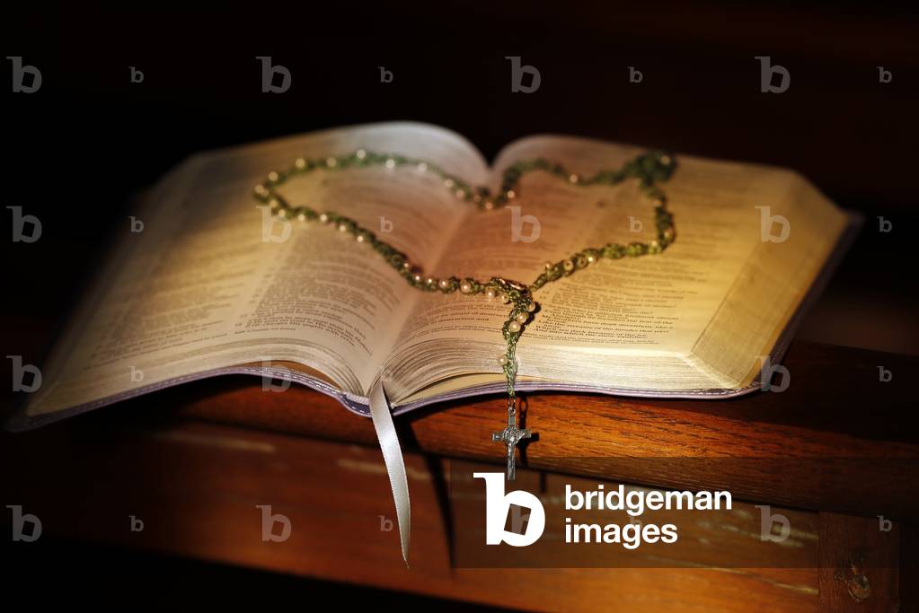 Open bible  and rosary in a church.  (photo)