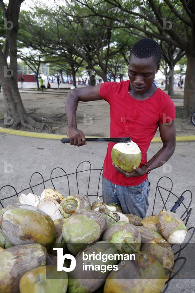 Man selling coconuts in Cotonou, Africa (photo)