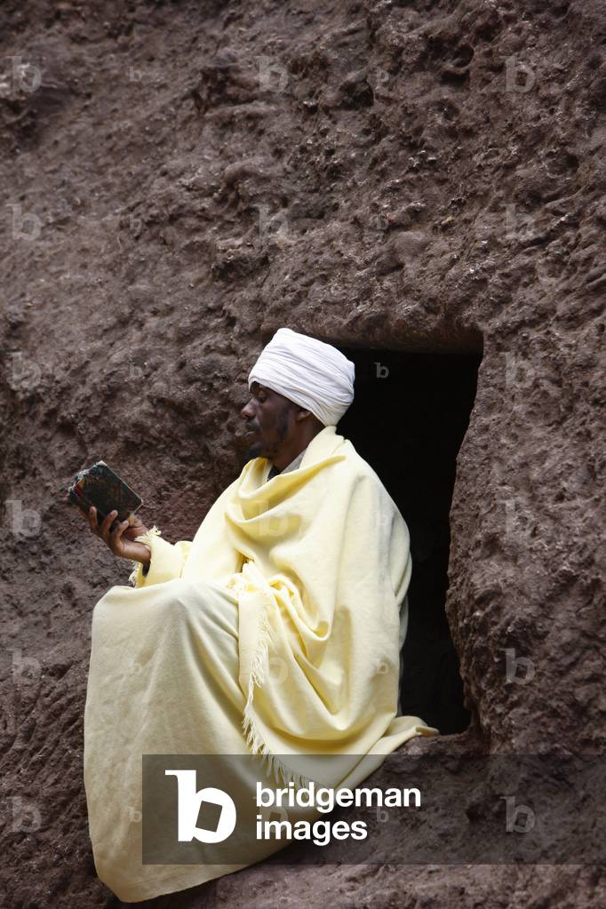 Faithful reading outside a church in Lalibela, Lalibela, Ethiopia