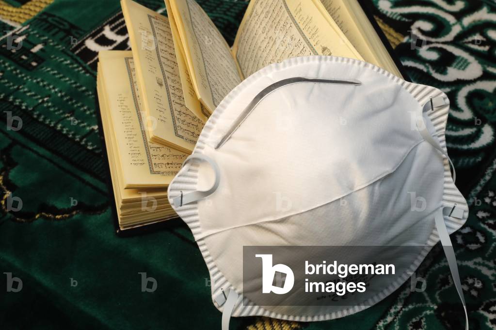 Religion and coronavirus (COVID-19), Quran and disposable surgical mask (photo)