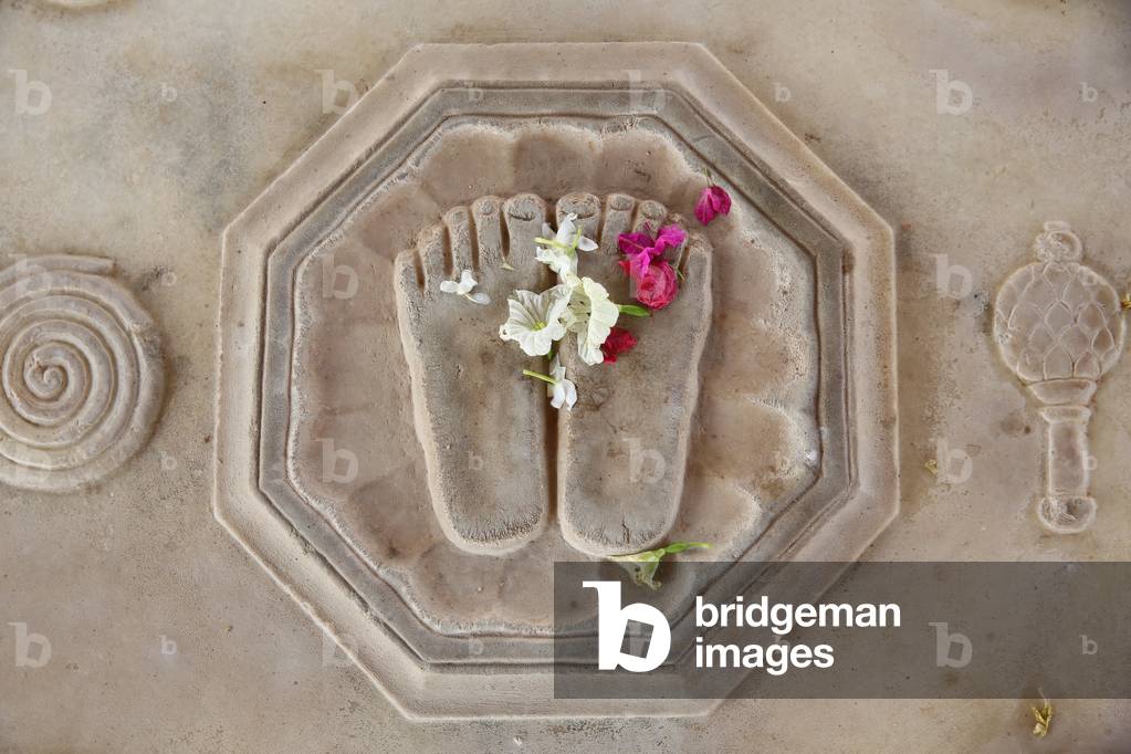 Flower offering on Krishna's lotus feet engraved on the floor in Kusum Sarovar. India