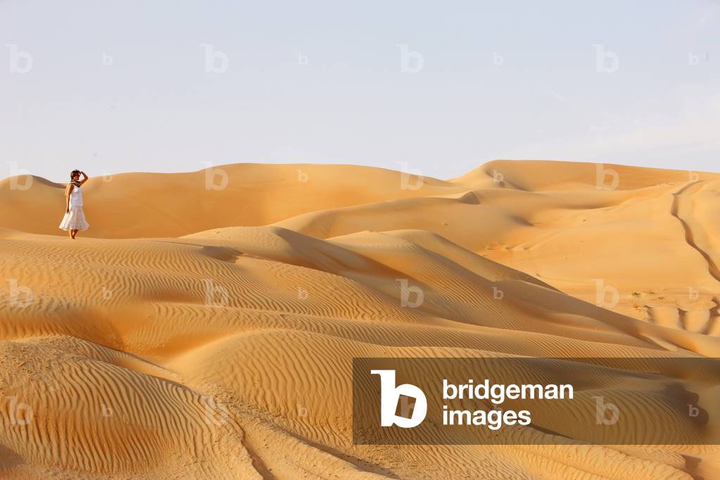 Woman walking in Liwa desert, Abu Dhabi, United Arab Emirates