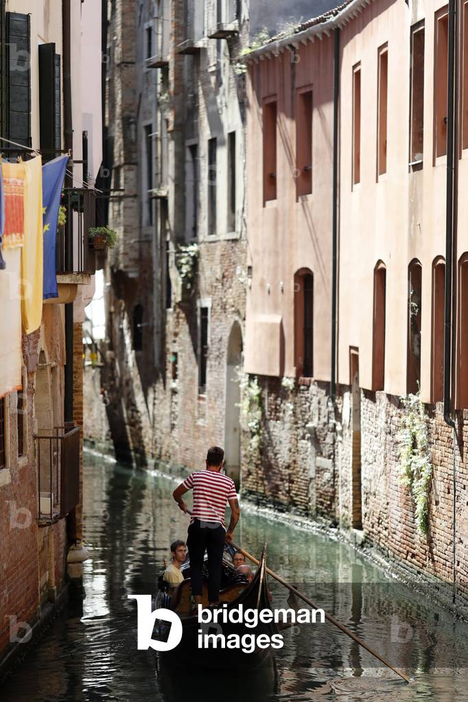 Gondola with tourists sailing on a water street.