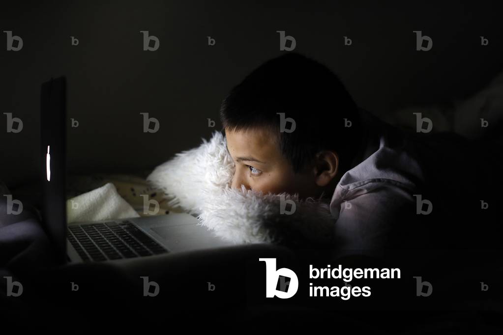 Boy staring at a computer screen at night in Montrouge, France