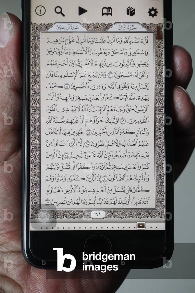 Man reading an electronic Quran on a smartphone,  (photo)