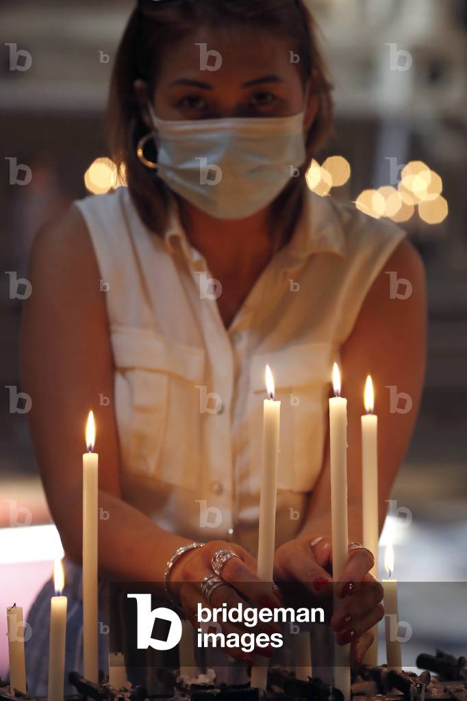 Woman with face mask praying in church during coronavirus epidemic.