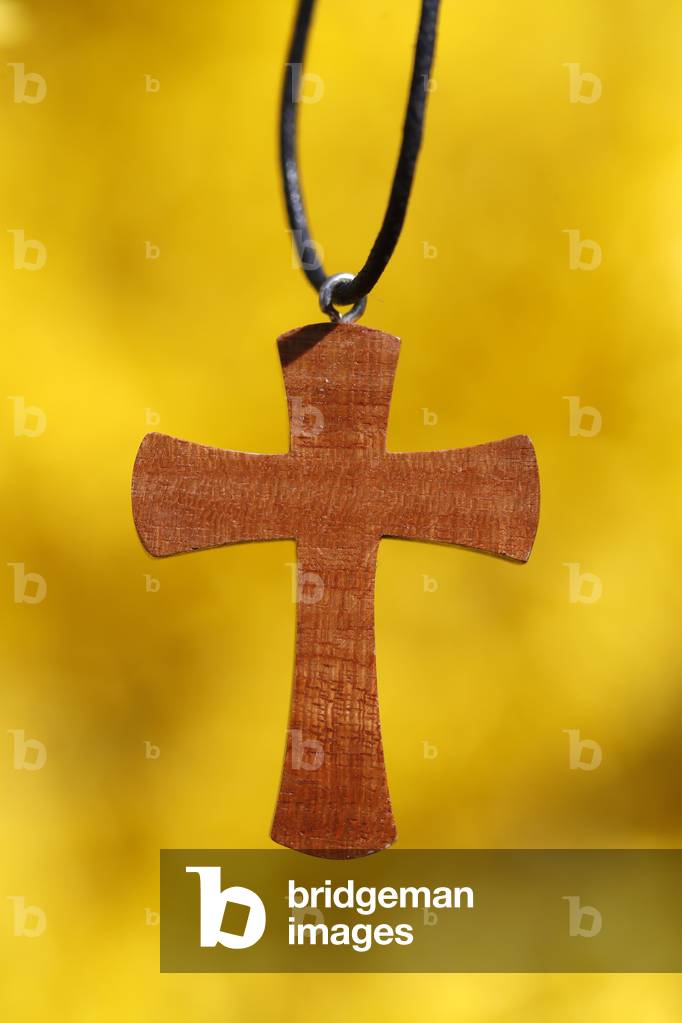 Cross pendant against yellow broom flowers (photo)