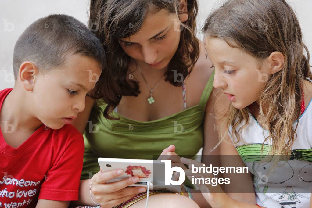 Children playing with a play station, Depressa, Italie